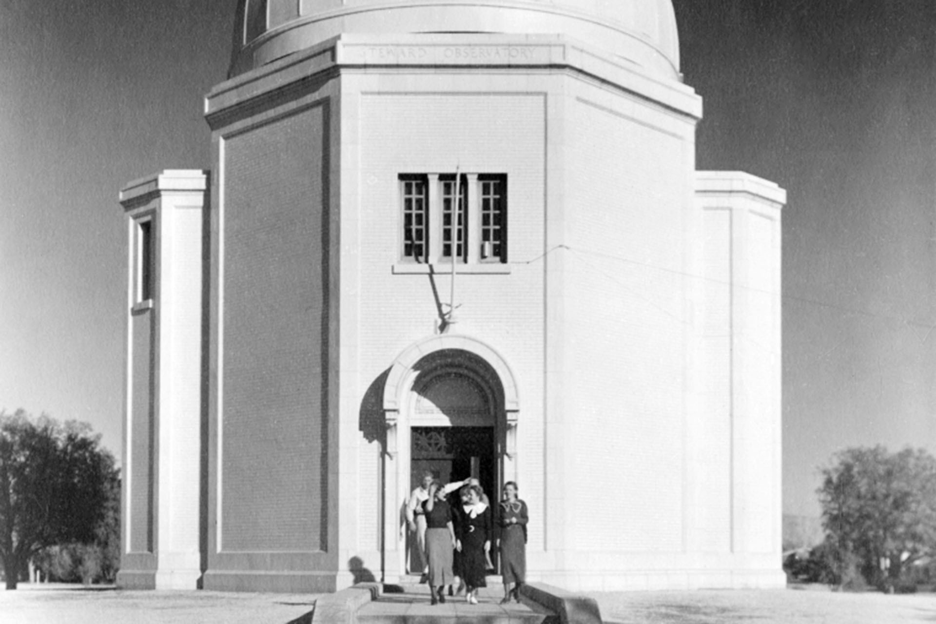 A photograph of five individuals standing outside of the Steward Observatory dome