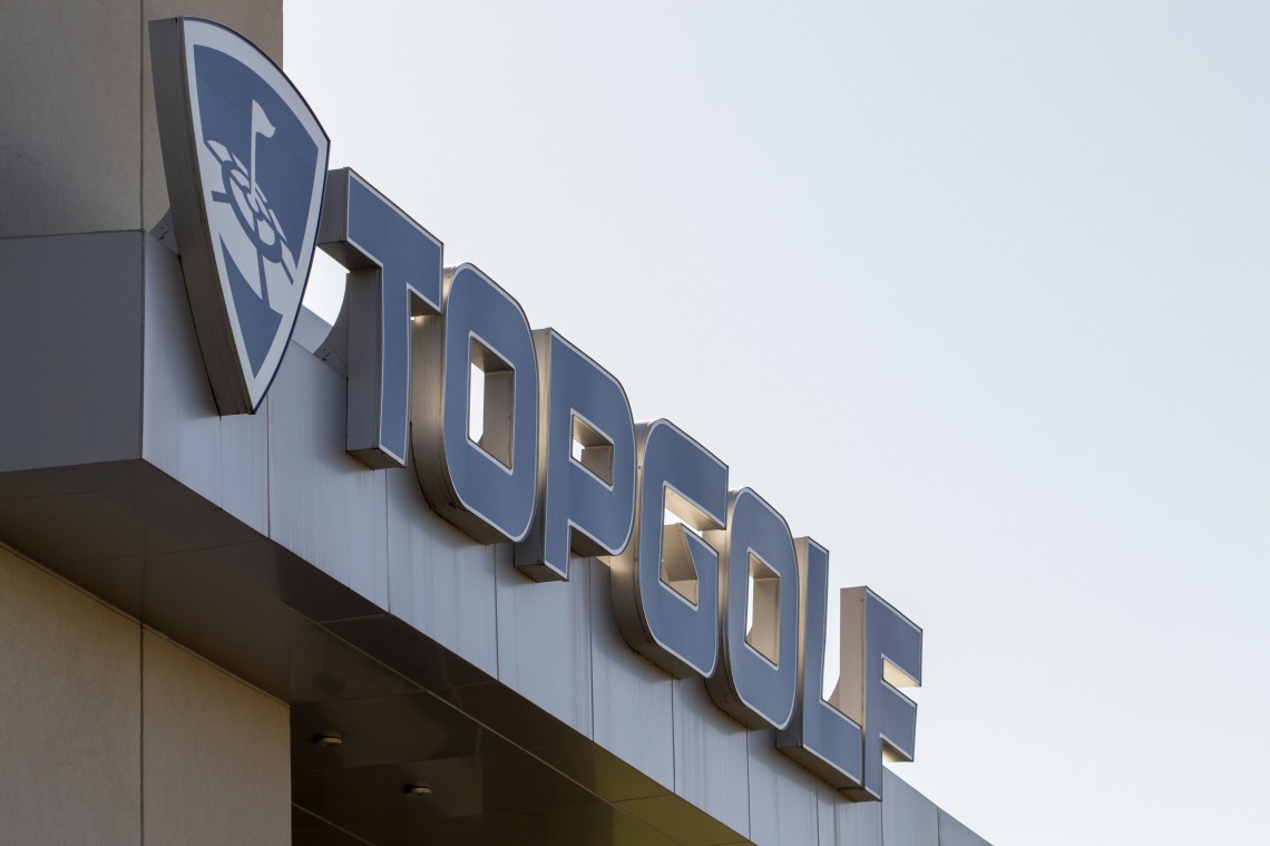A photograph of the Topgolf logo against a building