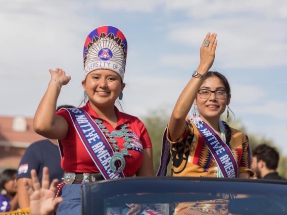 Two women in Native American dress, waving