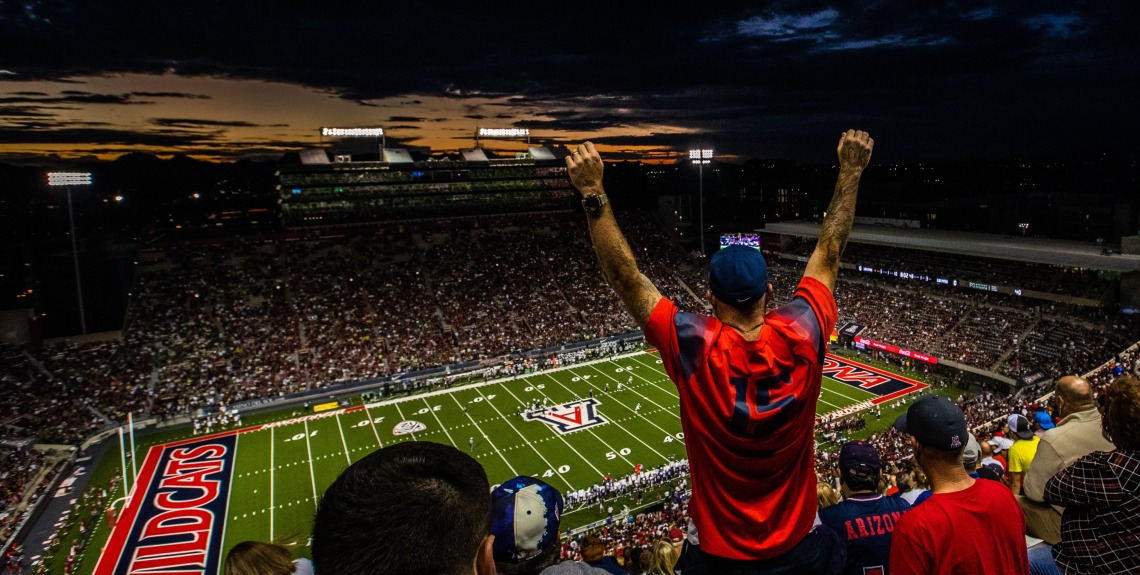 Man standing with arms raised in Arizona Stadium
