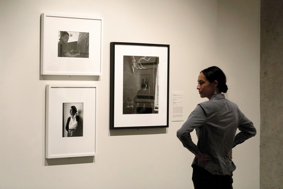 A photograph of a woman, with her hands on her hips, looking at photographs