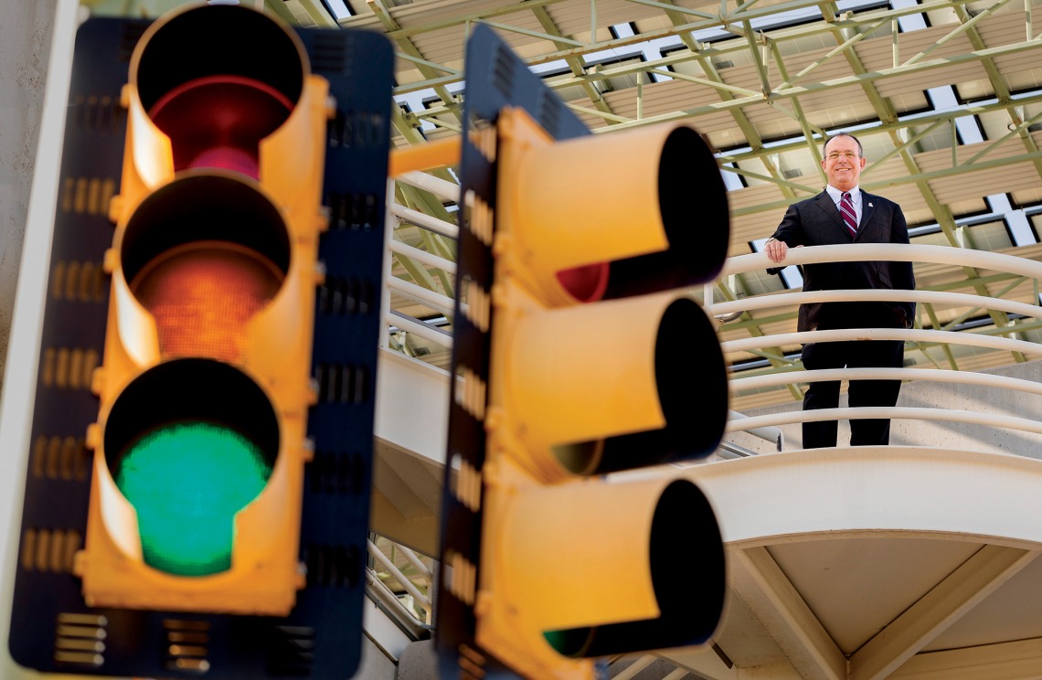A photograph of Larry Head standing behind a traffic light stop
