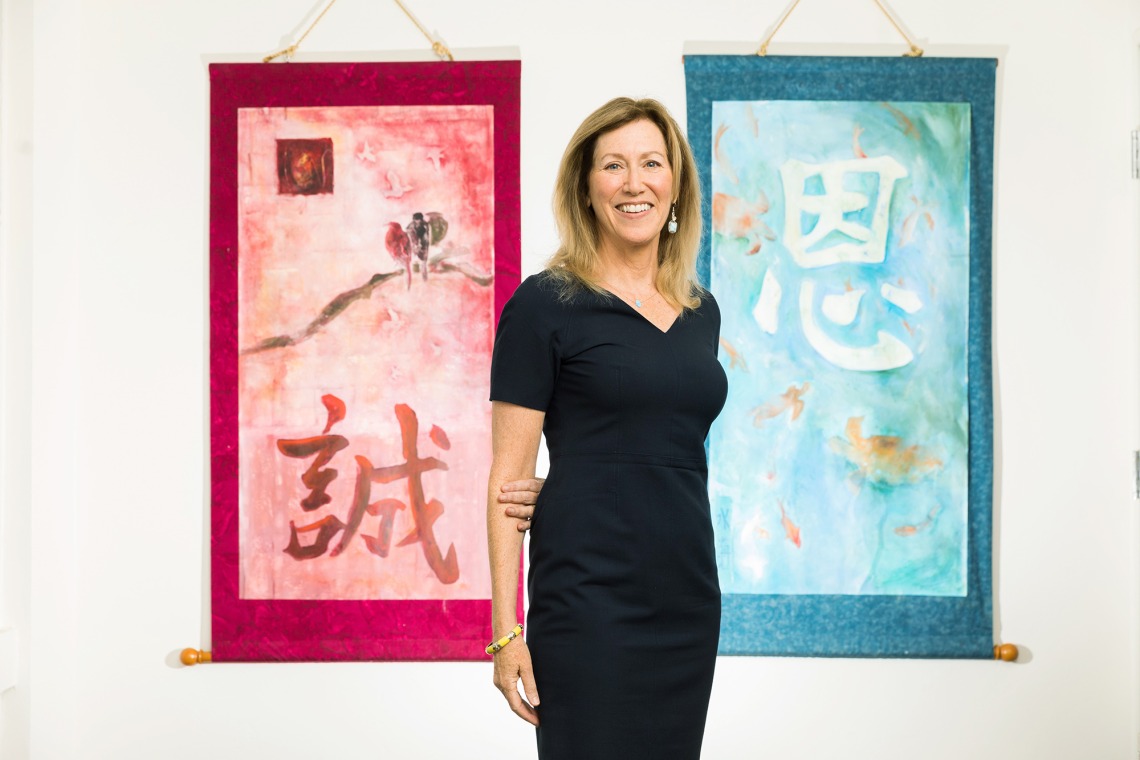A photograph of Dr. Victoria Maizes smiling in front of artwork