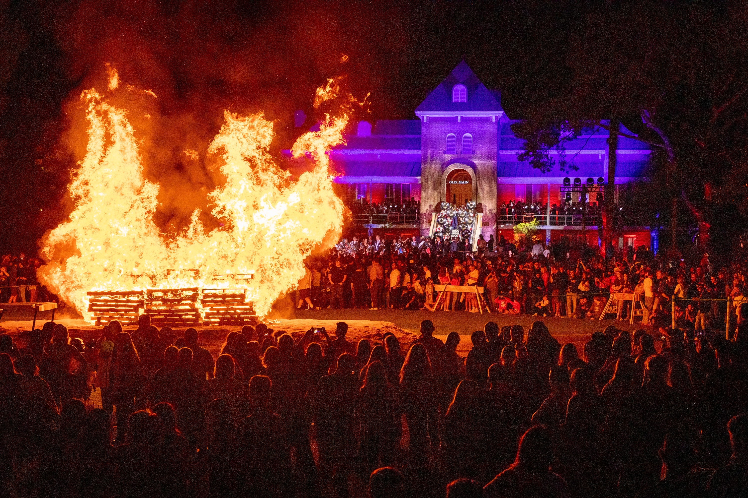 Large bonfire in front of Old Main with crowd surrounding it