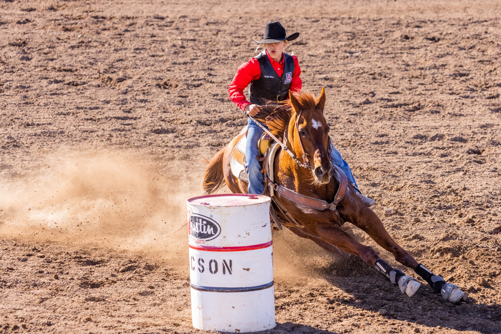 A photograph of Cyleigh Nelson competing in barrel racing at an intercollegiate rodeo held in Tucson