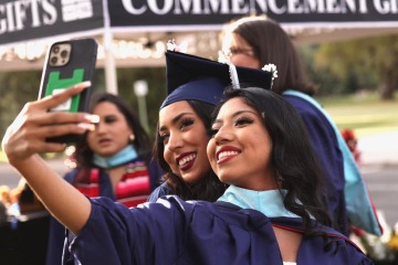 Two female students in graduation gowns taking a selfie