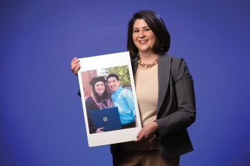 A photograph of Christina Noz holding a photograph from her graduation