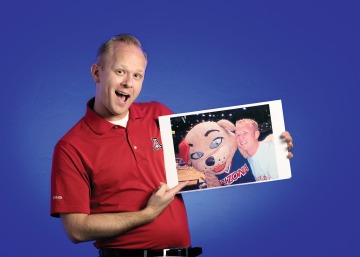 A photograph of David Henz holding a photo of him and Wilma the Wildcat