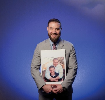 A photograph of Matt Hesketh holding a photo of him and his brother Ben