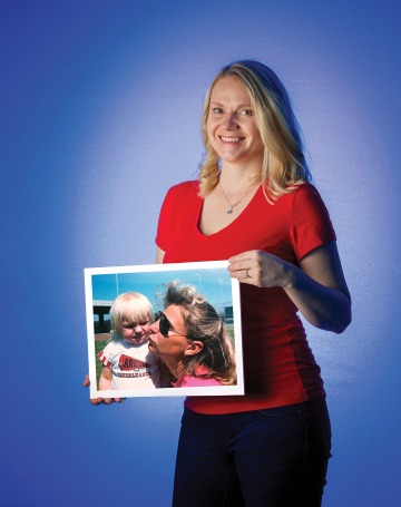 A photograph of Vanessa (Schatzberg) Chiaradonna holding a photograph of her mom kissing and embracing her as a young child